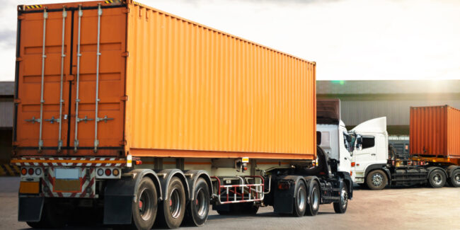 shipping-container-automotive-indstry A truck transporting a shipping container for conversion showcases its application in the automotive industry.